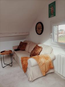 sala de estar con sofá y reloj en la pared en Appartement ! Petit nid entre pistes et lacs!, en Saint-Laurent-en-Grandvaux