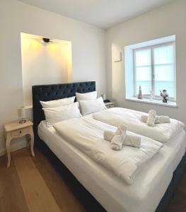 - un grand lit blanc avec deux animaux rembourrés dans l'établissement Palazzo Exclusiv Appartment, à Tegernsee