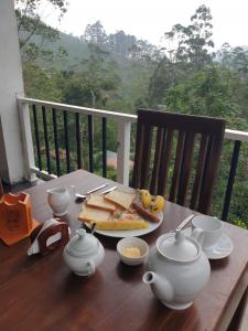 a wooden table with a plate of food and tea pots at Daddy's Guest Home in Adams Peak