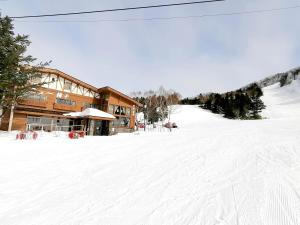 um alojamento de esqui numa pista coberta de neve em frente a um edifício em New Yokote em Yamanouchi