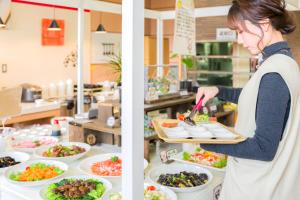 una mujer preparando comida en una cocina con platos de comida en Imari Grand Hotel en Imari