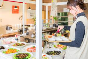 a woman preparing food in a kitchen with plates of food at Imari Grand Hotel in Imari