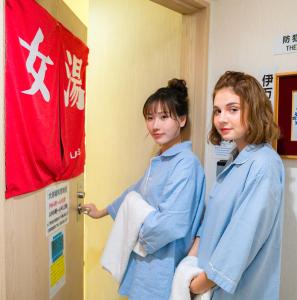 Due ragazze sono in piedi davanti alla porta di una stanza di Imari Grand Hotel a Imari