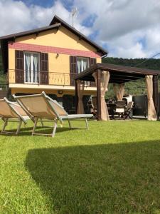 two lawn chairs and a house in the background at Casa Bea con Piscina e giardino in Caravonica