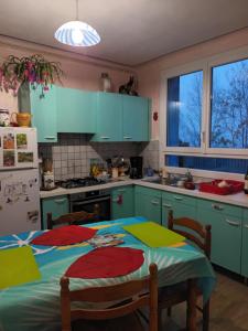 cocina con armarios azules, mesa y nevera en la petite maison bleue, en Jugon Les Lacs