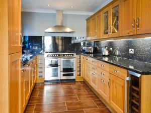 a large kitchen with wooden cabinets and a stove at Ashgrove in Mainsriddle