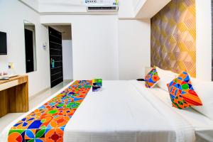 um quarto com uma grande cama branca e um cobertor colorido em FabExpress Marvel Bliss Viman Nagar em Pune