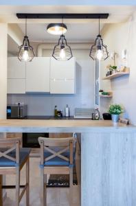 a kitchen with white cabinets and a counter with chairs at Amazing Modern Apartment with Sea View in Athens