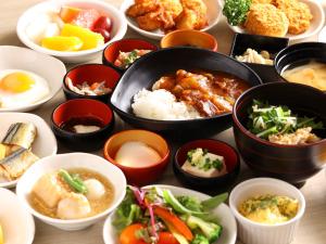 a table topped with bowls of different types of food at Dormy Inn Takasaki in Takasaki