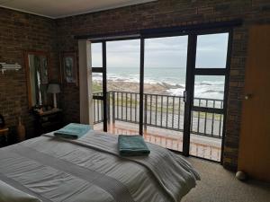 sypialnia z łóżkiem i widokiem na ocean w obiekcie Sonvanger w mieście Lambertʼs Bay