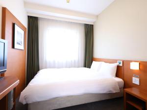 um quarto de hotel com uma cama e uma janela em Dormy Inn Takasaki em Takasaki