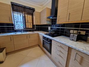 a kitchen with wooden cabinets and a stove and a window at Eric Wilkins Apartments in Kampala