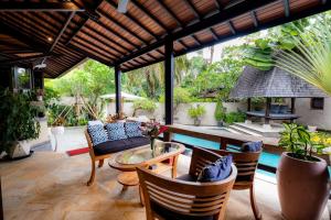 a patio with a table and chairs and a pool at Villa Frangipani Seminyak in Seminyak