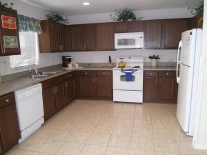 a kitchen with wooden cabinets and white appliances at 4 Bedroom Value Plus Home with Private Pool in Orlando