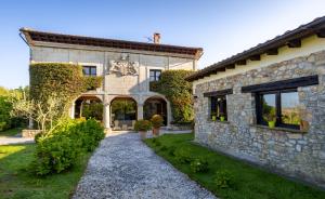 uma vista exterior para uma casa de pedra com um jardim em Casona Las Cinco Calderas em Galizano