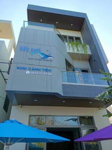 un edificio con un balcón con sombrillas delante en Canh Tien Homestay Tam Thanh Beach en Tam Kỳ