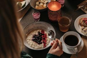 a woman is eating a bowl of oatmeal with berries at Lapland Hotels Ylläskaltio in Äkäslompolo