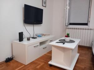 a white living room with a tv on a wall at BellaVista Apartmani in Stara Pazova +2 photos
