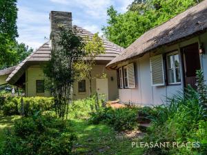 an old house with a thatched roof in a yard at Pleasant Places By Sanaandi in Lidgetton