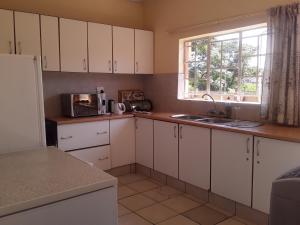 a kitchen with white cabinets and a sink and a window at Vuya Nathi Bed and Breakfast in Manzini