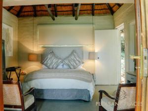um quarto com uma cama e 2 cadeiras em Pleasant Places By Sanaandi em Lidgetton