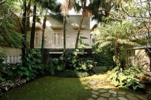a white house with palm trees in front of it at Huize Betsy in Bandung