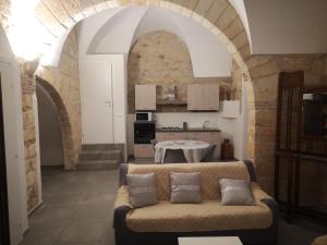a living room with a couch in front of a kitchen at Casa Archi in Castelvetrano Selinunte +7 photos