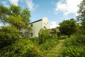 a white house surrounded by grass and trees at Stonehaven Eco Cabins in Hermanus
