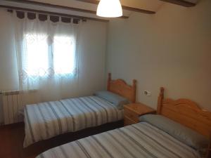 2 Betten in einem kleinen Zimmer mit Fenster in der Unterkunft Valdelinares Apartamentos in Valdelinares
