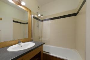 een badkamer met een wastafel, een bad en een spiegel bij B406- Appartement 2 pieces cabine 6 personnes in Orcières