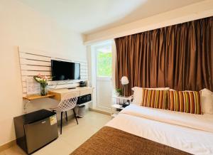 um quarto de hotel com uma cama, uma secretária e uma televisão em Bayshore Inn em Hong Kong