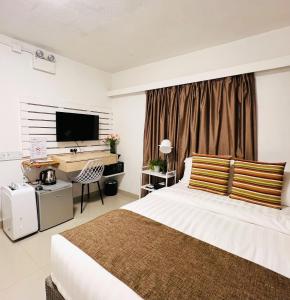een slaapkamer met een bed, een bureau en een televisie bij Bayshore Inn in Hong Kong