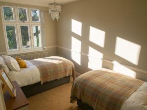 a bedroom with two beds and two windows at The Beeches - Chatsworth Apartment No 1 - Sleeps 4 in Baslow