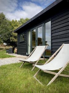 two chairs sitting in the grass in front of a house at Meadow View - Bottom Cabin in Foolow