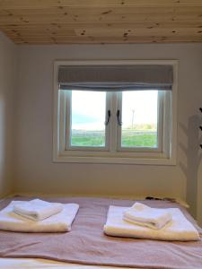 two towels on a bed in front of a window at Meadow View - Bottom Cabin in Foolow