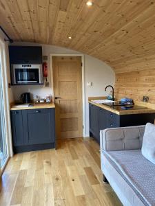 una cocina con armarios azules y un sofá en una habitación en Meadow View - Bottom Cabin, en Foolow