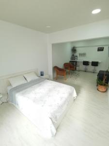 a white bedroom with a large bed and chairs at Habitación con entrada independiente in Vigo