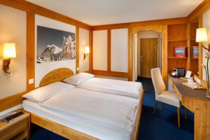 a hotel room with a bed and a desk and a desk at Derby Swiss Quality Hotel in Grindelwald