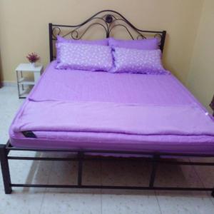 uma cama roxa com lençóis e almofadas roxos em HOMESTAY KAKMAH em Jasin