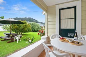 um alpendre com uma mesa e cadeiras brancas e um guarda-sol em Whare Nui on Rennie - Thames Holiday Home em Thames