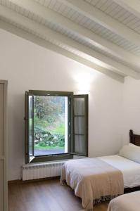 a white room with two beds and a window at Casa Rural Monte Zarro in Cudillero