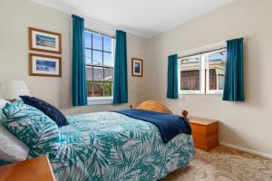 a bedroom with a bed and two windows at Whare Nui on Rennie - Thames Holiday Home in Thames