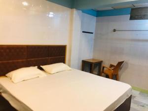 um quarto com uma cama branca e uma cadeira em Royal Rasool Residency em Paramagudi