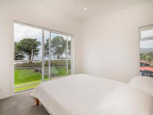 a bedroom with a white bed and a large window at Black House Lookout - Kuaotunu Holiday Home in Kuaotunu +25 photos
