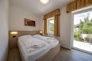 a bedroom with a bed with white sheets and a window at Appartamenti Stefan in Campitello di Fassa