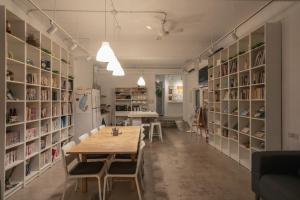 une salle à manger avec une table et des étagères de livres dans l'établissement Ruifang Yi Hostel, à Ruifang
