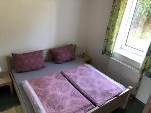 Bett in einem Zimmer mit lila Kissen und Fenster in der Unterkunft Villa Bella Vista - Meerblick 2 in Sassnitz