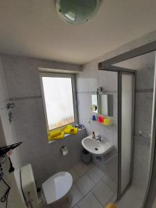 uma casa de banho com um lavatório, um WC e uma janela. em Villa Bella Vista - Meerblick 2 em Sassnitz