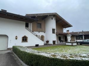 a white house with a hedge in front of it at Design Apartment Westendorf by Alpine Host Helpers in Westendorf