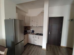 a kitchen with a stainless steel refrigerator and white cabinets at Bakuriani apartament in Bakuriani